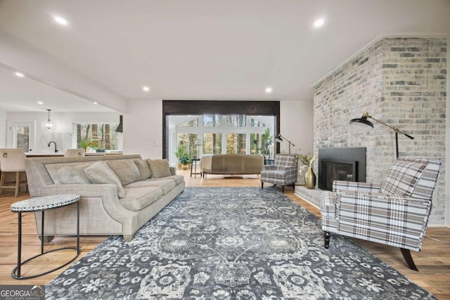 living room with a brick fireplace and hardwood / wood-style floors