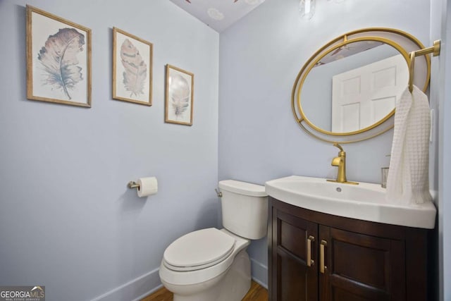 bathroom with wood-type flooring, vanity, and toilet