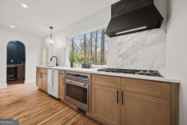 kitchen with black gas stovetop, stainless steel oven, sink, custom range hood, and beverage cooler