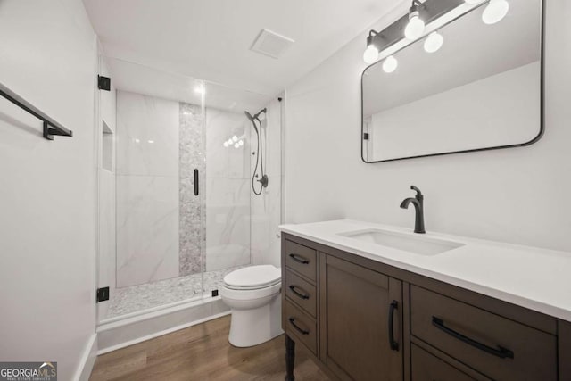 bathroom featuring vanity, toilet, a shower with shower door, and hardwood / wood-style floors