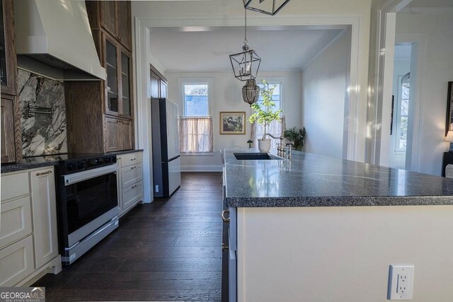 kitchen with extractor fan, fridge, white cabinetry, electric range, and a kitchen island with sink