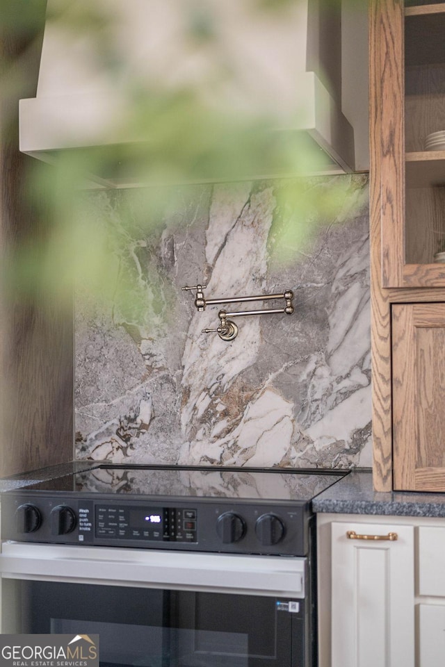 room details with white cabinets, electric range, and backsplash