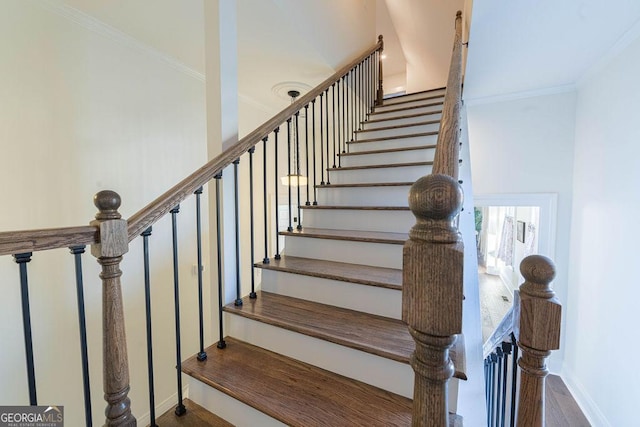 staircase with wood-type flooring and ornamental molding