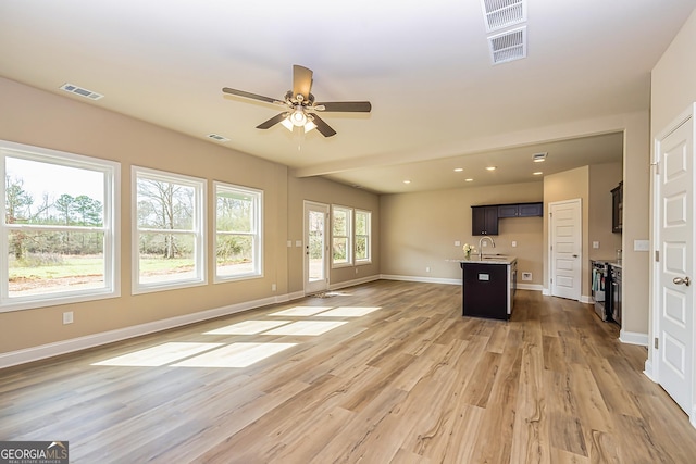 unfurnished living room with hardwood / wood-style flooring, ceiling fan, and sink