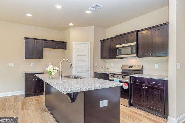 kitchen featuring sink, a kitchen island with sink, stainless steel appliances, and light hardwood / wood-style floors