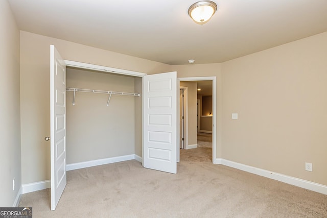 unfurnished bedroom featuring light carpet and a closet