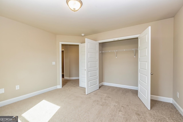 unfurnished bedroom with light carpet and a closet