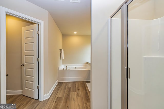 bathroom with independent shower and bath and wood-type flooring