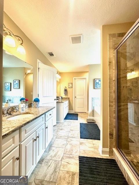 bathroom featuring vanity, a textured ceiling, and walk in shower