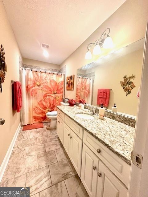 bathroom featuring toilet, a textured ceiling, and vanity