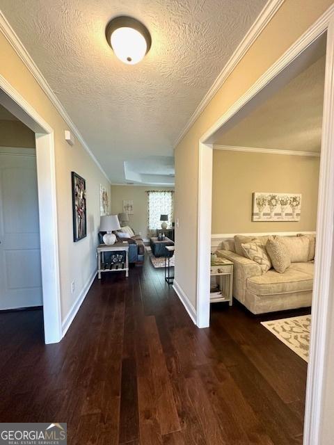 hall featuring a textured ceiling, dark wood-type flooring, and crown molding