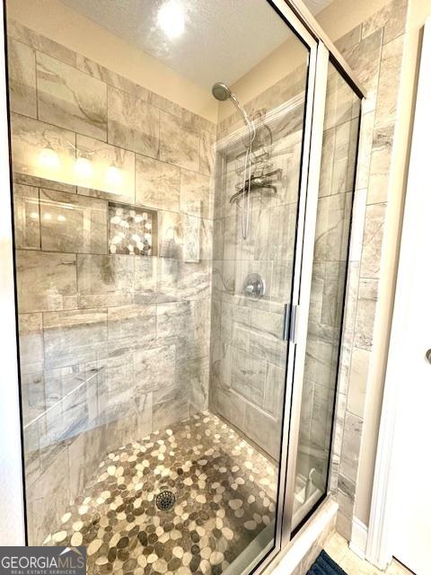 bathroom featuring a shower with shower door and a textured ceiling