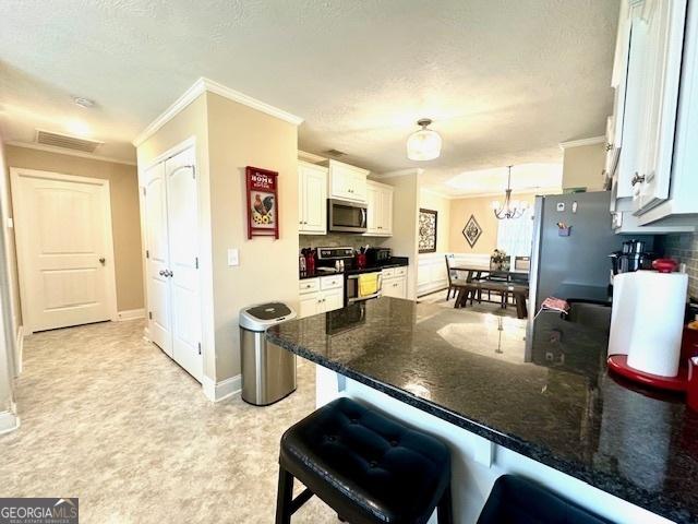 kitchen featuring appliances with stainless steel finishes, white cabinets, decorative light fixtures, a breakfast bar, and kitchen peninsula