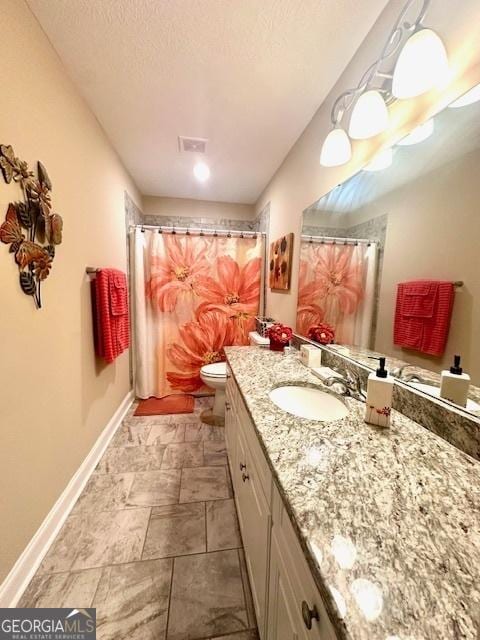 bathroom featuring a textured ceiling, toilet, and vanity