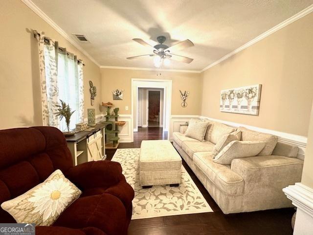 living room with ornamental molding, dark hardwood / wood-style floors, and ceiling fan