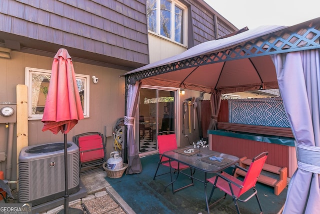 view of patio featuring a gazebo, fence, cooling unit, and a hot tub