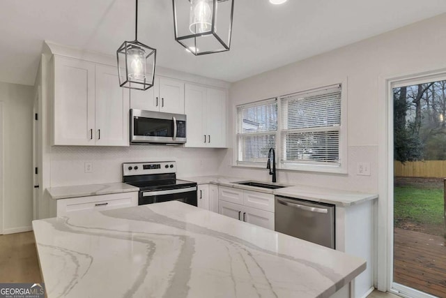 kitchen featuring appliances with stainless steel finishes, decorative light fixtures, sink, and white cabinets