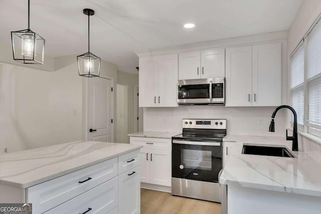 kitchen with decorative light fixtures, sink, stainless steel appliances, and white cabinets