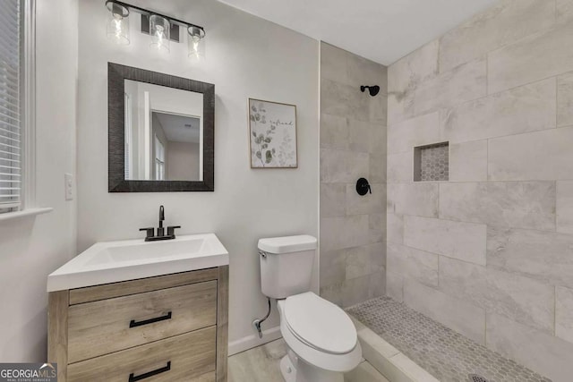 bathroom featuring vanity, tiled shower, and toilet