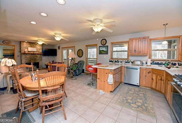 kitchen featuring a fireplace, kitchen peninsula, hanging light fixtures, stainless steel appliances, and light tile patterned floors