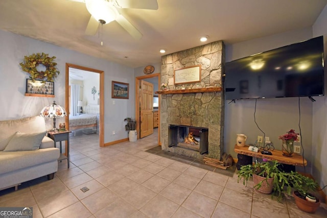 living room with light tile patterned flooring, ceiling fan, and a stone fireplace