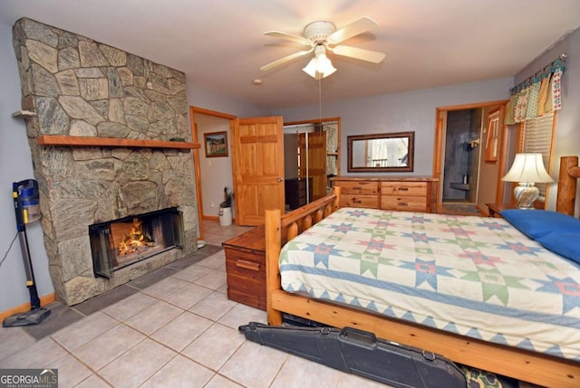 tiled bedroom featuring ceiling fan and a stone fireplace