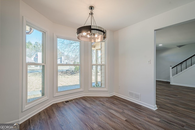 unfurnished dining area featuring dark wood finished floors, visible vents, and a notable chandelier