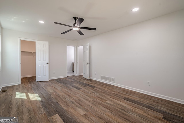 unfurnished bedroom with visible vents, a walk in closet, dark wood finished floors, recessed lighting, and baseboards