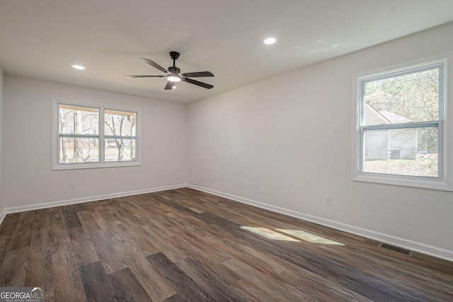 unfurnished room featuring dark wood finished floors, visible vents, a healthy amount of sunlight, and baseboards