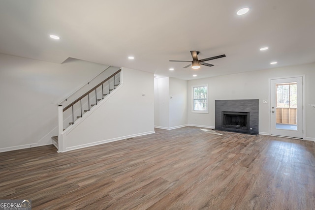 unfurnished living room featuring recessed lighting, stairway, wood finished floors, and a fireplace