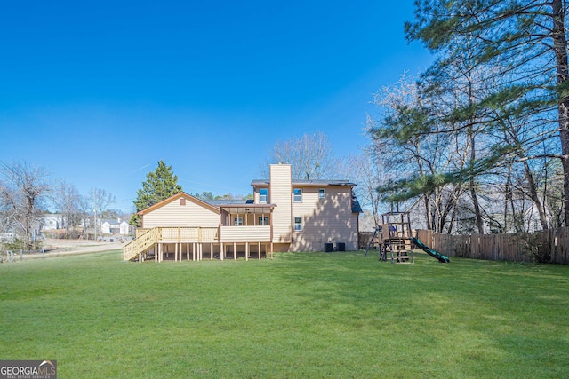 back of house featuring a sunroom, fence, a lawn, and a playground