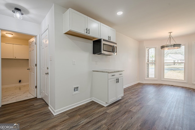 kitchen with baseboards, dark wood-style flooring, hanging light fixtures, white cabinetry, and stainless steel microwave