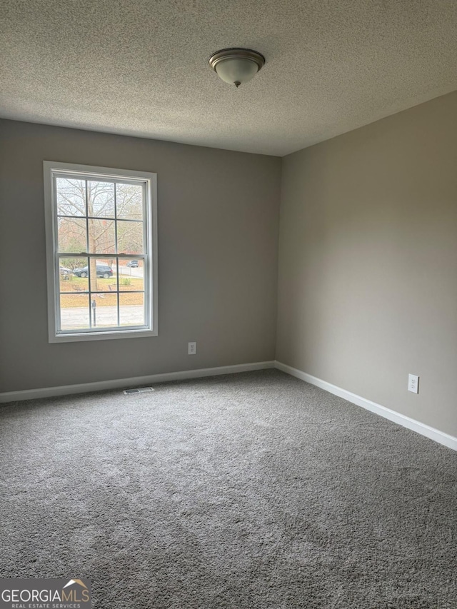 empty room with a textured ceiling and carpet flooring