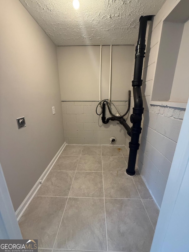 clothes washing area with light tile patterned floors, hookup for an electric dryer, and a textured ceiling