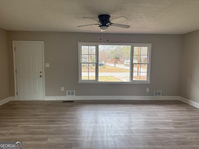 unfurnished room featuring light hardwood / wood-style flooring, ceiling fan, and a textured ceiling