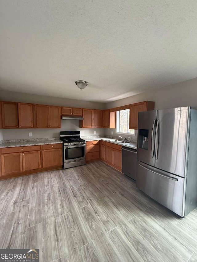 kitchen with sink, light hardwood / wood-style floors, stainless steel appliances, and a textured ceiling