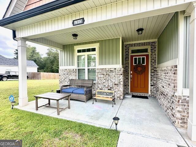 view of exterior entry featuring a patio and a lawn