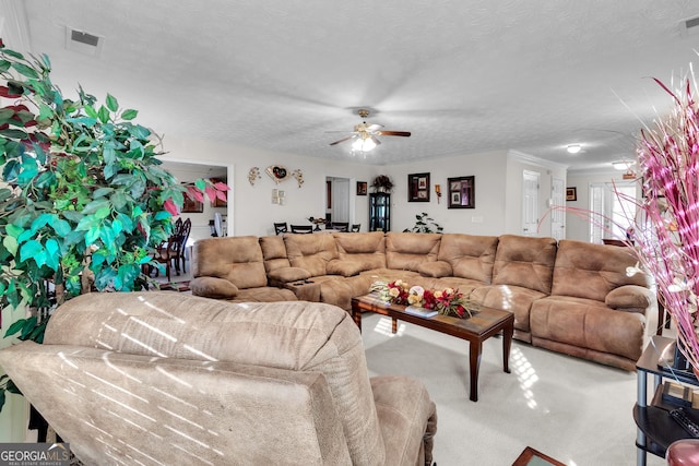 living area with a textured ceiling, a ceiling fan, visible vents, and light colored carpet