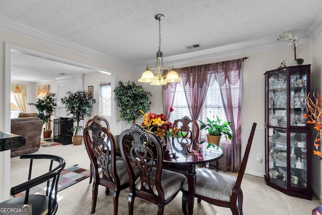 dining room with a textured ceiling, light colored carpet, visible vents, ornamental molding, and an inviting chandelier