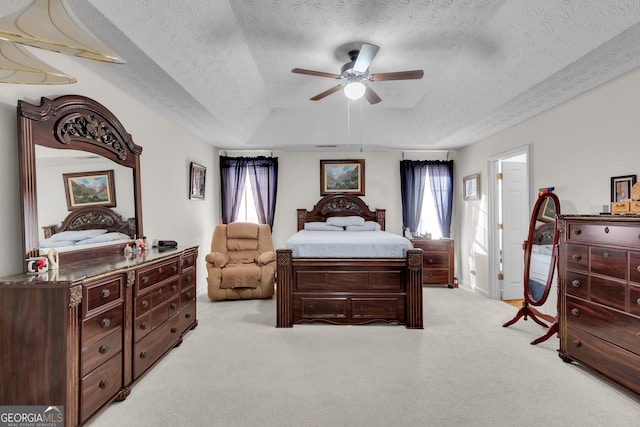 bedroom featuring light carpet, multiple windows, a tray ceiling, and a textured ceiling