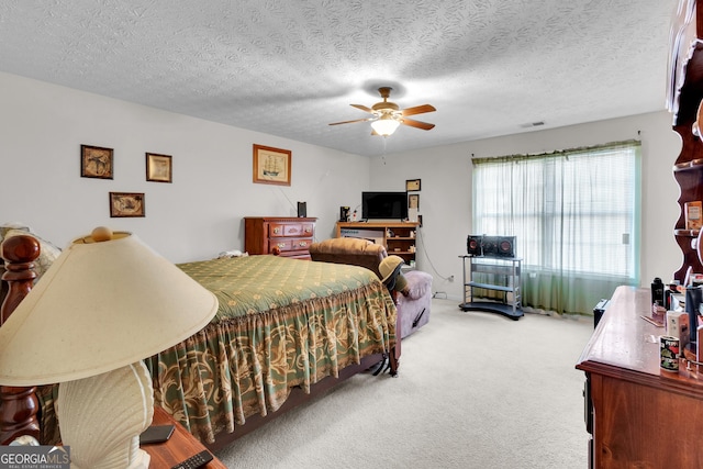 carpeted bedroom with a ceiling fan, visible vents, and a textured ceiling