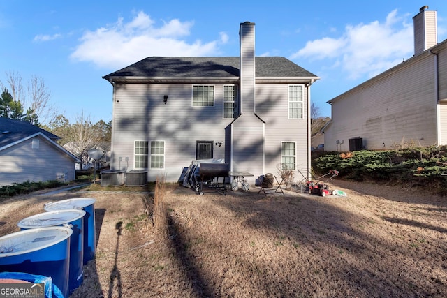 rear view of house featuring a chimney and central AC unit