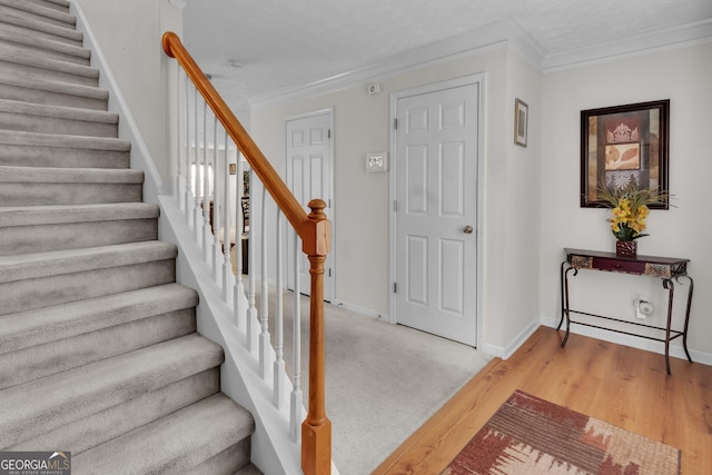 stairs with crown molding, baseboards, and wood finished floors