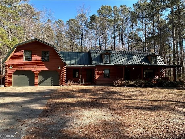 log-style house featuring a standing seam roof, dirt driveway, log siding, and a gambrel roof