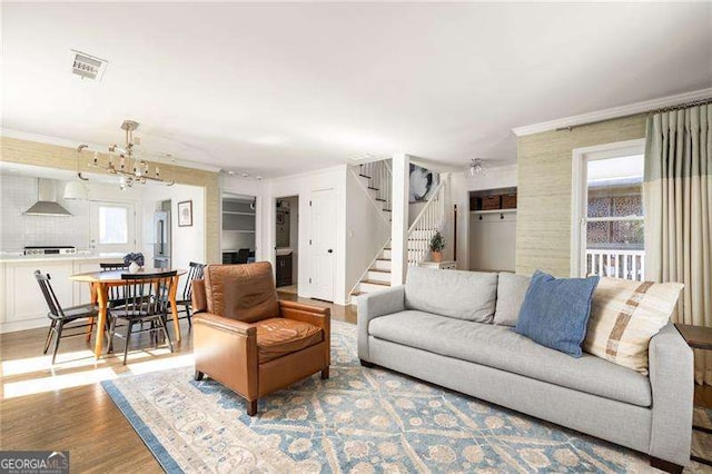 living room with ornamental molding, light hardwood / wood-style floors, and an inviting chandelier