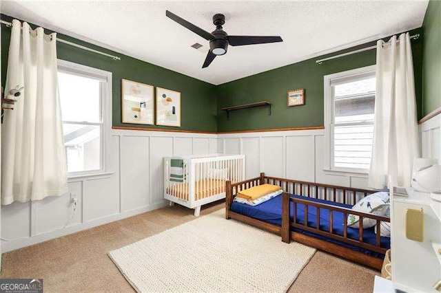 carpeted bedroom featuring multiple windows and ceiling fan