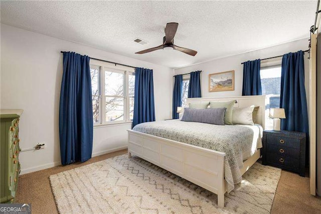 bedroom with light colored carpet, ceiling fan, and a textured ceiling