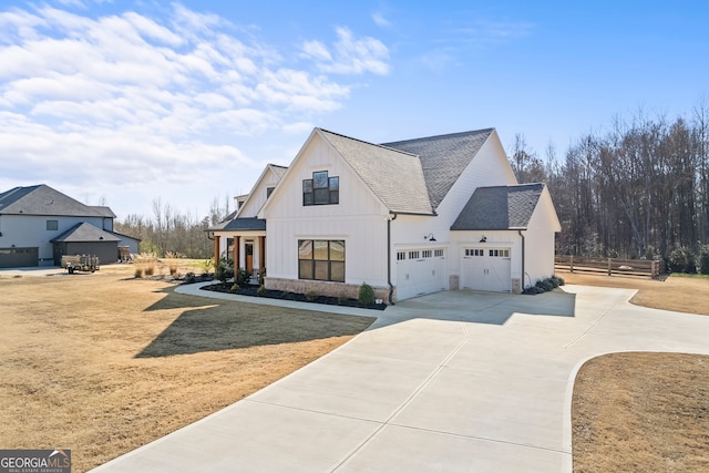 view of side of home with driveway, a yard, board and batten siding, roof with shingles, and a garage