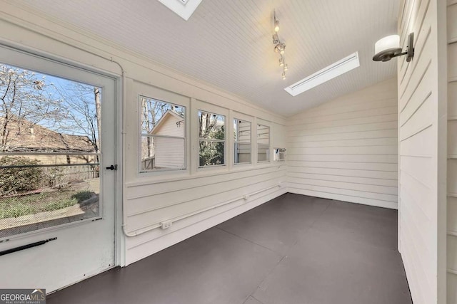 unfurnished sunroom with track lighting and lofted ceiling with skylight