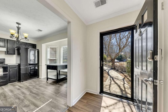 entrance foyer featuring ornamental molding, light hardwood / wood-style flooring, an inviting chandelier, and a textured ceiling